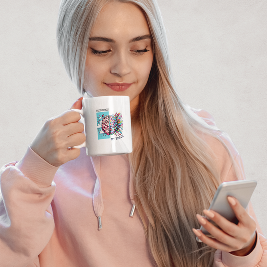 Woman holding a white mug that shows “Your Brain vs My Brain” with a split brain glitch design – Funny neurodivergent mug by Mentally Glitched.